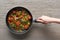 Cropped view of woman holding frying pan with omelet with mushrooms, tomatoes and greens.