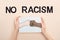 Cropped view of woman holding picture with drawn multiethnic hands doing fist bump near no racism lettering