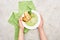 Cropped view of woman holding plate with delicious creamy green vegetable soup with croutons near green napkin.