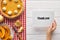 Cropped view of woman holding thank you card near sweet pumpkin pie on wooden white table with apples.