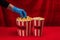 Cropped view of woman in latex glove taking popcorn from bucket on red surface with velour