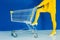 Cropped view of woman leaning on shopping cart on blue background