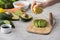 Cropped view of woman squeezing lemon on cut avocado on cutting board.