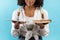 Cropped view of young black female student holding book and tablet pc, comparing offline studies and online learning