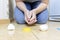 Cropped woman sitting on a kitchen floor and ready to remove broken egg with a tissue from kitchen floor