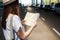 Cropped Young traveler tourist woman in hat with backpack searching route in paper map at international airport. Female