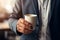 Cropper view of A businessperson holding a coffee cup stands isolated against a softly blurred background. AI Generated