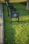 A cropping of blue wooden bench on fresh green grass in a small park with a nice sunlight casting.