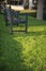A cropping of blue wooden bench on fresh green grass in a small park with a nice sunlight casting.
