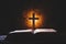 Cross with bible and candle on a old oak wooden table. Beautiful gold background.