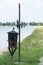 Cross and Candle Placed in the Grass near the Lake