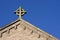 Cross on church roof on blue sky in Islington London UK
