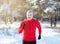 Cross country running in winter. Happy fit senior man jogging in snowy forest on sunny morning