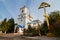 Cross and crucifix with a flowerbed in the yard of Dormition of the Mother of God modern russian Orthodox church