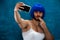 Cross dressing person in blue wig with smartphone