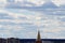 Cross on the golden spire of a Babtist church in the afternoon against a cloudy sky over the horizon in the city of