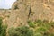 The Cross on an impregnable cliff in mountains opposite the entrance of the rock-cut Medieval Geghard Monastery complex.