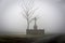 Cross with jesus next to tree at junction in mist