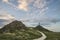 Cross in landscape of Ynys Llanddwyn Island with Twr Mawr lighthouse in background with blue sky