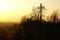 A cross monument overlooking a misty city landscape at sunset