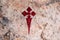 Cross of Santiago in red paint on a rock in a religious cave