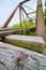 Cross shaped nail head on textured wood of distant blurred railroad bridge and tacks