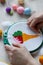 Cross stitch embroidery of color ice cream with woman hands and color balls of yarn on white wooden table