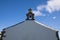 Cross symbol with bell on rooftop of church rising up in sky