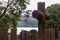 Cross and tombstones in cemetery with lake in background