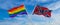crossed flags of lgbt and confederate battle or Dixie flag flag waving in the wind at cloudy sky. Freedom and love concept. Pride
