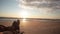 Crossed legs of a person lying on a sandy beach enjoying beautiful pastel sunset with boots on