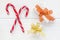 Crossed peppermint candy canes and gift boxes on white wooden background