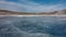 Crossing cracks are visible on the blue ice of the frozen lake.