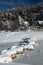 Crossing frozen lake on snowy rocks in winter scenic idyll in Kranjska Gora in blue sky, Slovenia