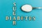 Crossing the words `sugar` and `diabetes`, a spoon with sugar on a blue background, concept