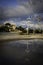 Crosswalk sign with pond reflection on a cloudy day with dark blue sky