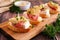 Crostini appetizers with brie cheese, salami and artichokes, close up on a serving board against a wood background