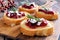 Crostini appetizers with cranberry sauce, cheese, rosemary on wooden server