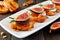 Crostini appetizers with figs, brie cheese and nuts, close up on a serving plate against wood