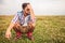 Crouched casual man in a grass field thinking