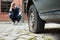 Crouched Man Pointing At Punctured Car Tire