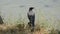 A crow sits on a stone by the lake with turtles and holds food in its beak