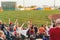 a crowd in chairs watching a game with spectators holding up their hands