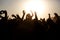 The crowd enjoys the summer music festival, sunset, the silhouettes hands up