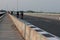 A crowd of people gathered on the road built on the river bridge and some players cycled