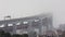 A crowd of people running half marathon on the bridge in a thick white fog