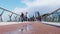 Crowd of people walking by pedestrian glass bridge with a bicycle path