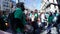 Crowd of people wearing green t-shirts and holding and playing drums in street.