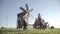 Crowd in Russian folk costumes is dancing outdoor on traditional antique wooden windmill background. Group of happy