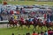 Crowd of spectators, cars & jockeys riding horses fast and speedy at Champ de Mars Racecourse